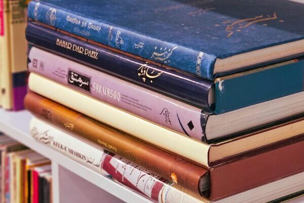 Stack of colorful books on a shelf in an Iranian library, showcasing Persian literature.